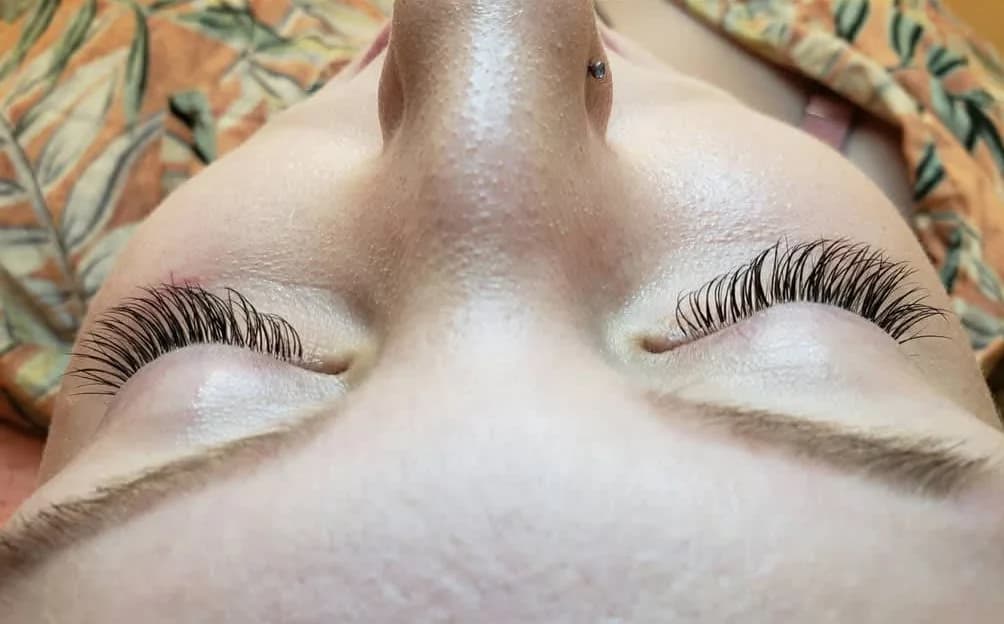 A finished lash set seen from above, the client lying back with her eyes closed