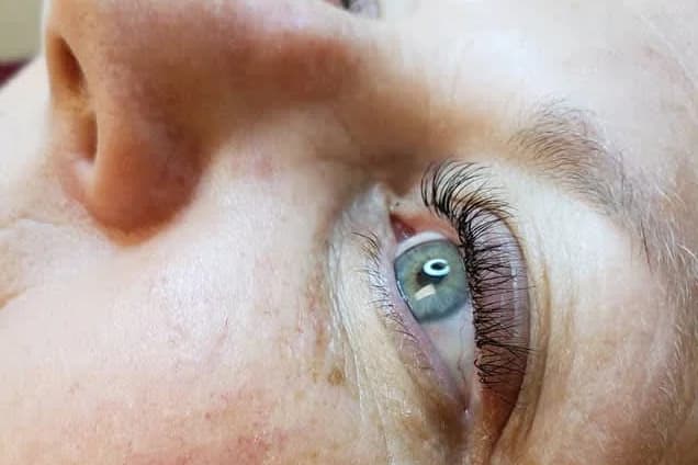 A client's eye in profile with a full, dark set of lash extensions along the upper lid