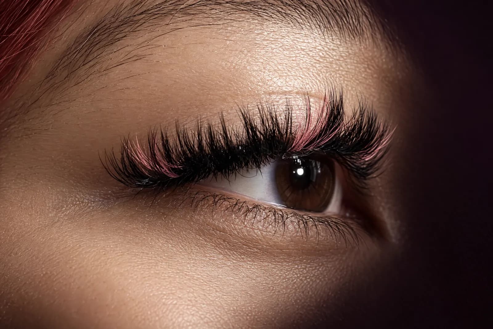 A fluffy black lash set with soft pink accent lashes on an open brown eye