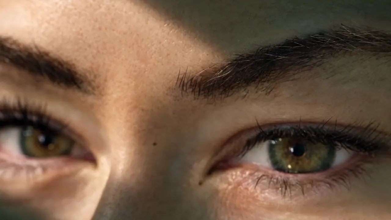 Dark, full brows and lash extensions on hazel eyes, with a slant of warm light across them