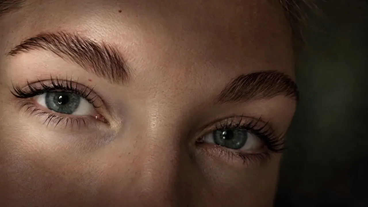 Green eyes under full, brushed-up brows, looking into the camera in warm light
