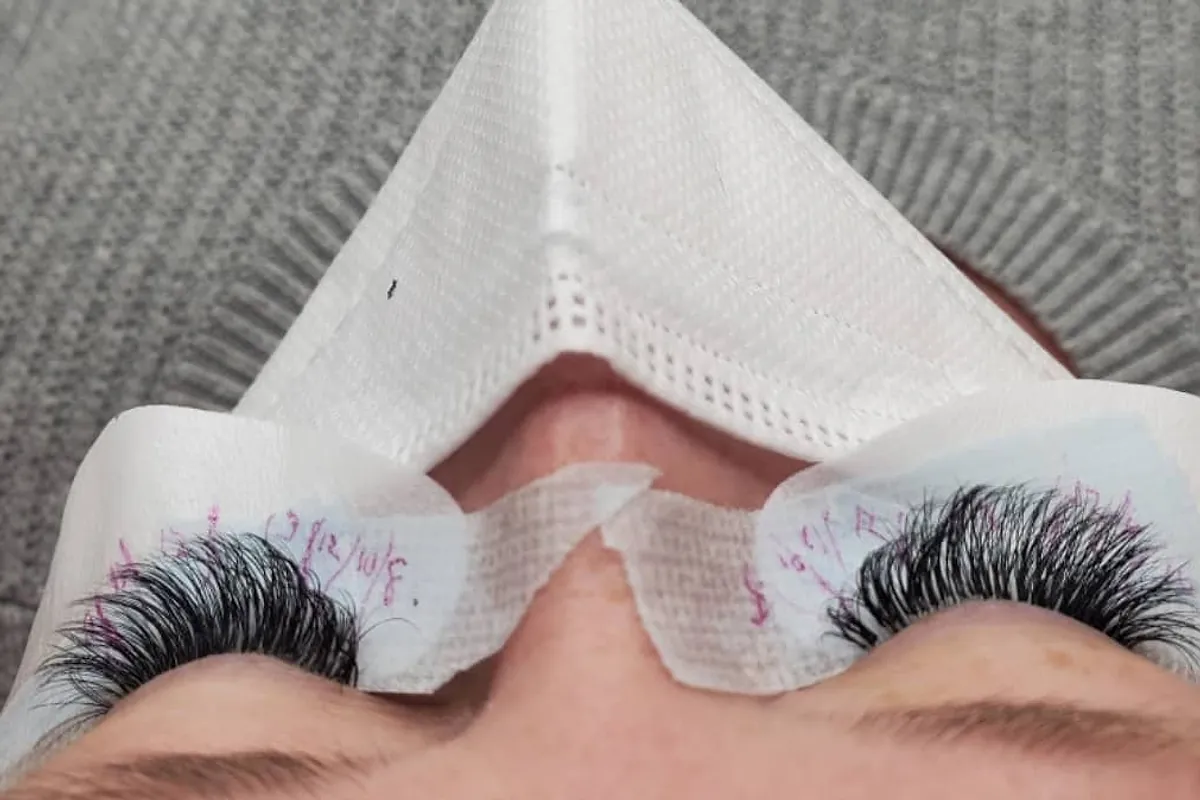 A finished lash set seen from above, with lash mapping notes written on the under-eye pads
