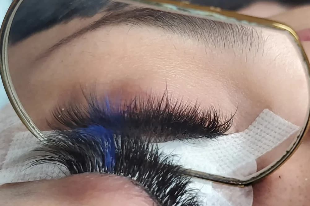Dark lash extensions with a streak of blue, seen through a lash loupe